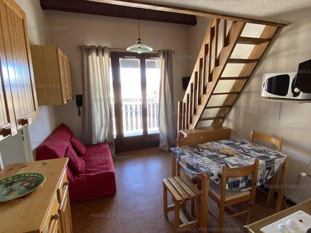 a kitchen and dining room with a table and a staircase at Charmant studio cabine mezzanine pour 4 personnes, proche centre, casier à skis - FR-1-295-130 in Les Angles