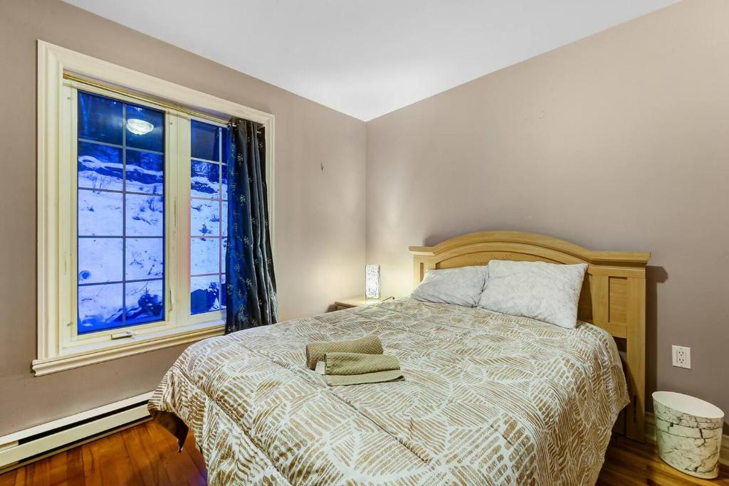 a bedroom with a bed and a large window at Cozy Chalet Val Morin in Val-Morin