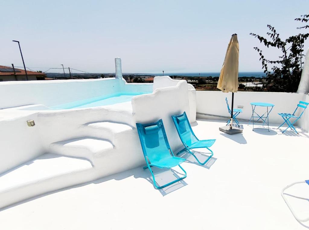 マリーナ・ディ・ラグーザにあるVilla Afrodite mediterranea 2022の椅子とプールのあるパティオ
