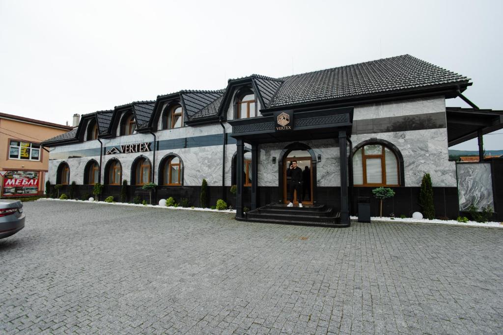 a building on a cobblestone street in front at Готель-ресторан Vertex in Tyachiv