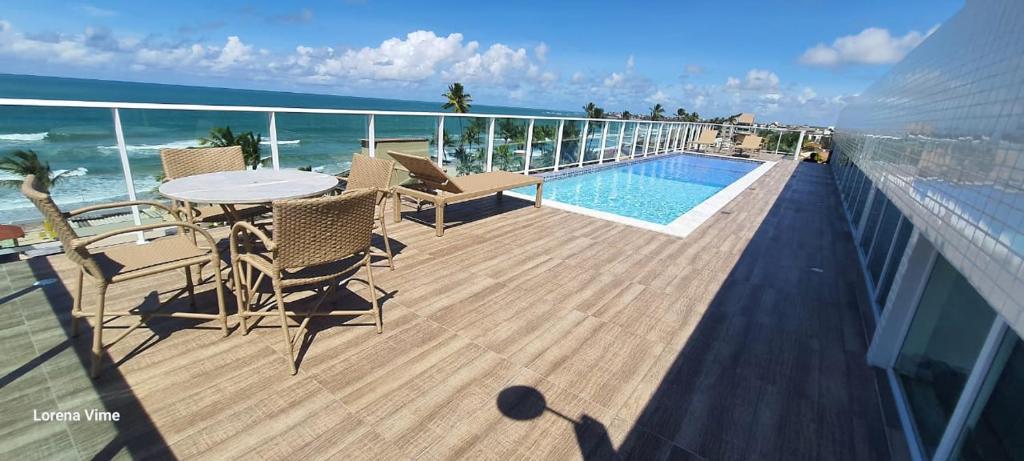 a balcony with a table and chairs and a swimming pool at Studio Al Mare - Ocean Blue in Porto De Galinhas