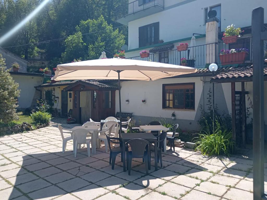 Un patio con mesas y sillas y una sombrilla. en Claudia B&B, en Pescasseroli
