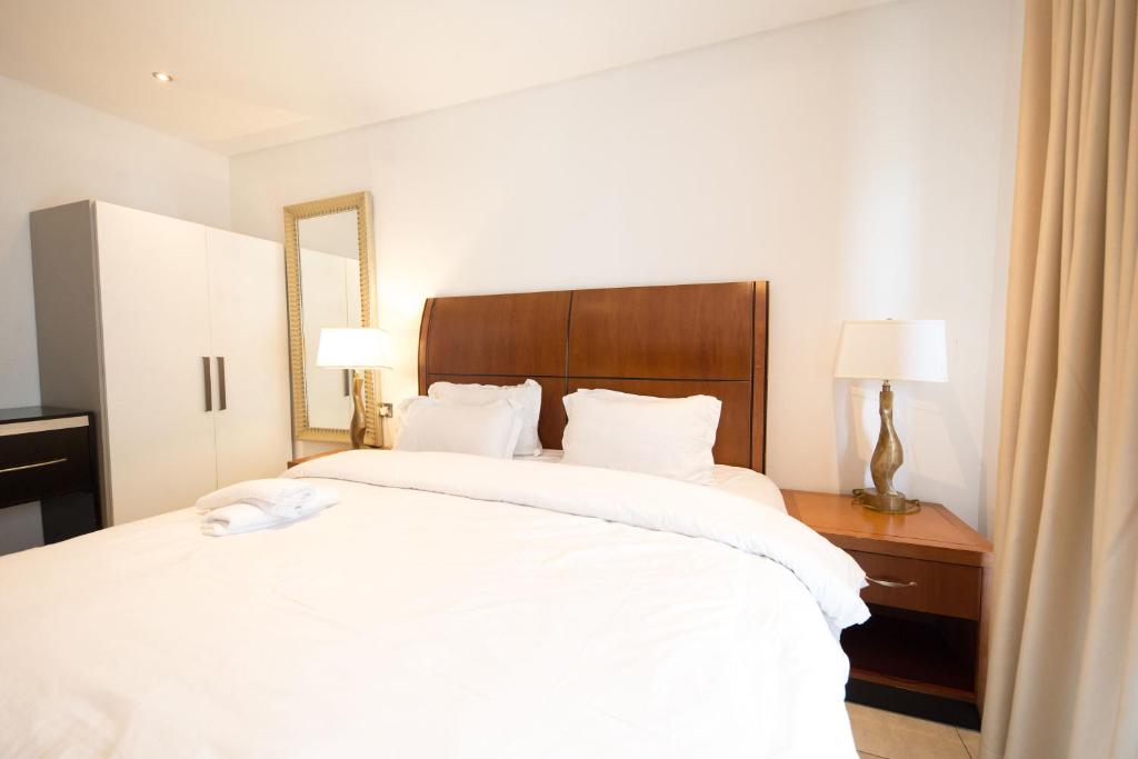 アクラにあるThe Signature Apartment Unit A407-Charming stay in Accra with AC, Free WiFiの木製のヘッドボードが付いた大きな白いベッドのある寝室