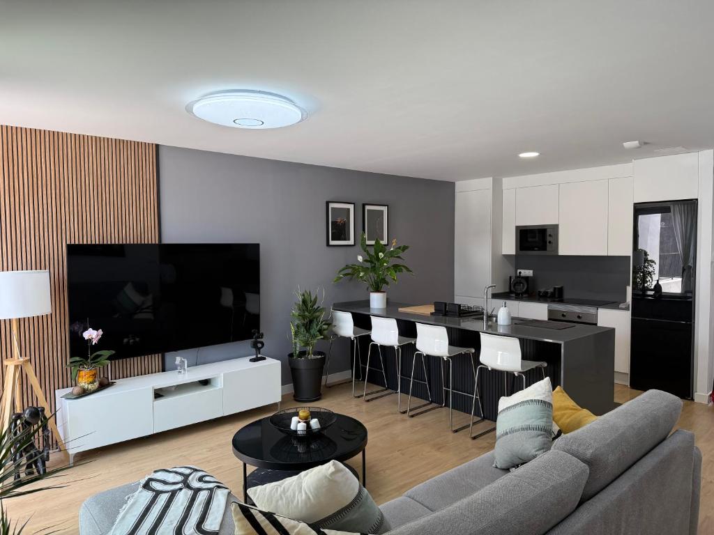 a living room with a gray couch and a kitchen at Abades confort & luxury in Abades