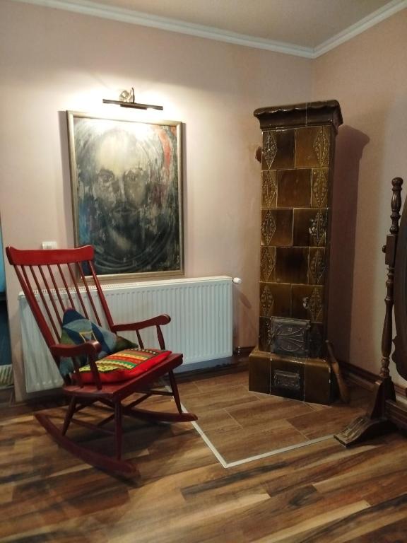a red rocking chair in a room with a fireplace at Guesthouse 2207 in Sremski Karlovci