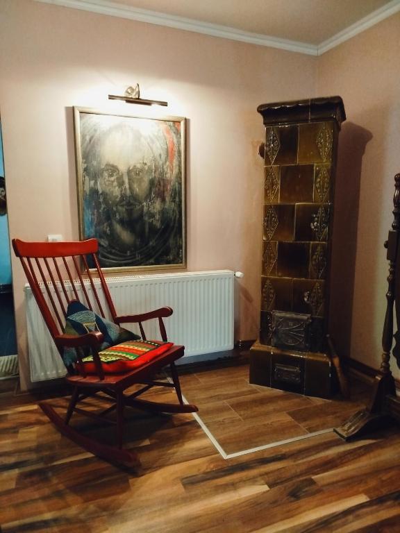 a red rocking chair in a room with a fireplace at Guesthouse 2207 in Sremski Karlovci