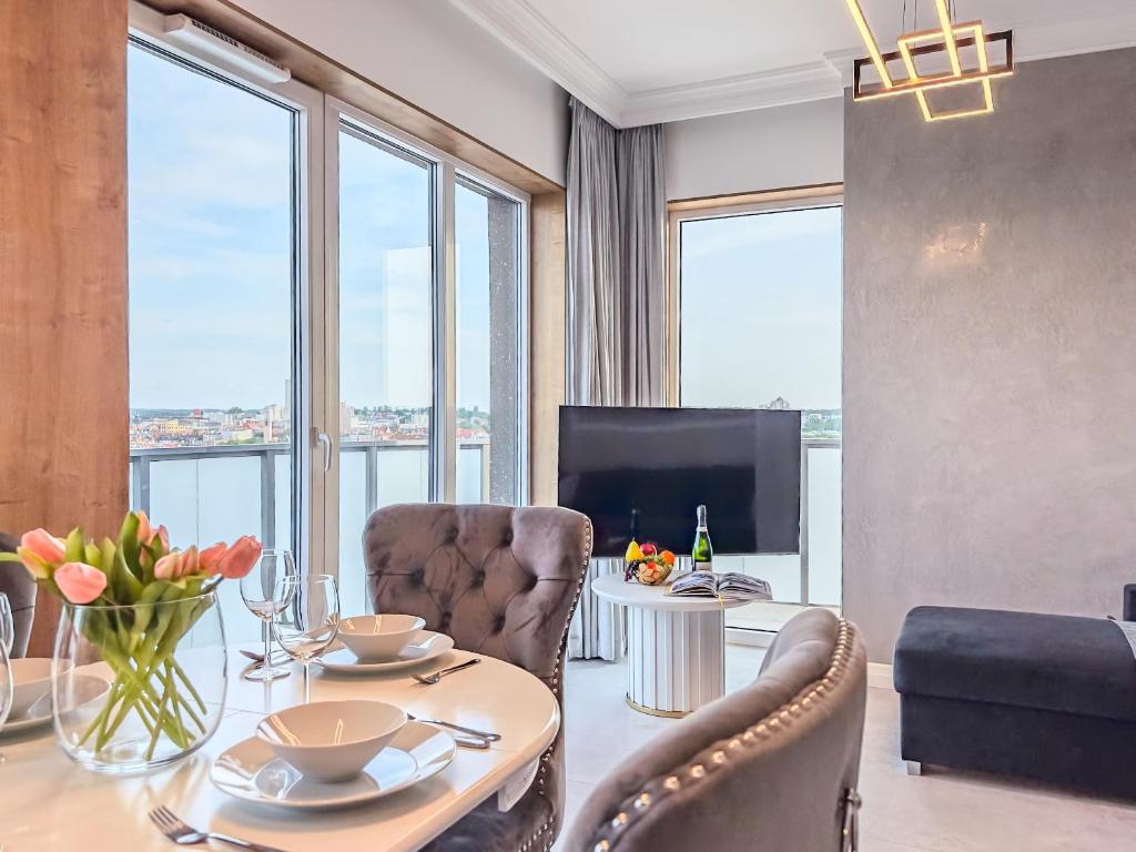a living room with a table and chairs and a television at URBAN APARTMENTS GLOBAL SKYLINE, 15th Floor No 23, Free Garage, Self Check-in, No Deposit in Katowice