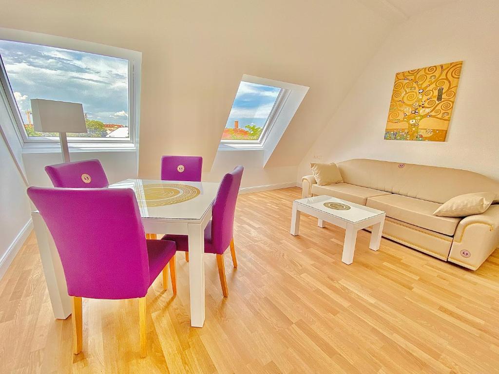 a living room with a table and purple chairs at Steiner Residences Mödling in Mödling