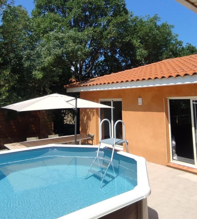 a pool with a chair and an umbrella at Villa vacances in Les Cluses