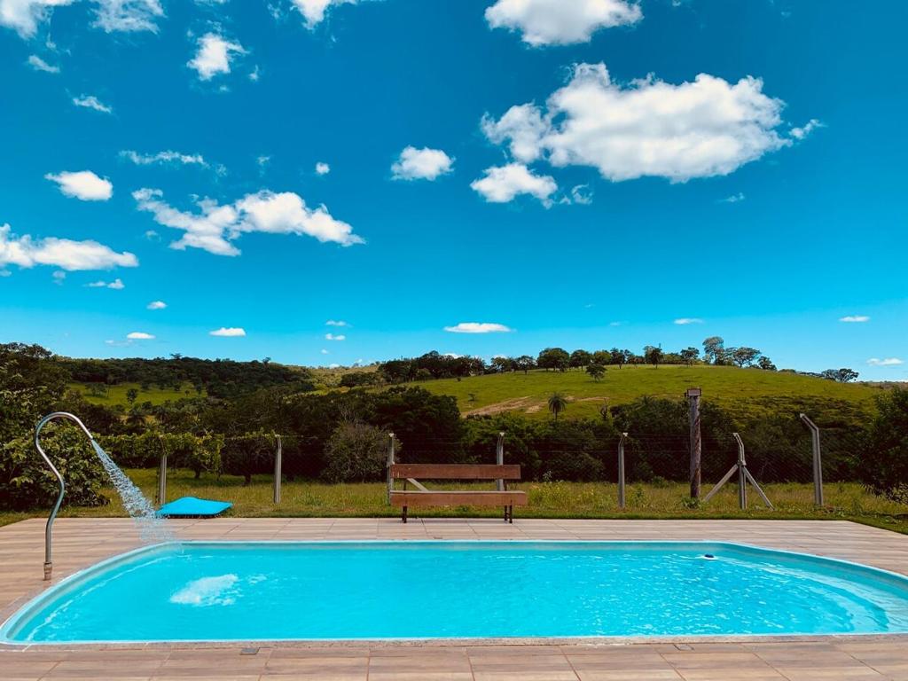 a swimming pool with a bench and a blue sky at Fazendinha LS in Lagoa Santa