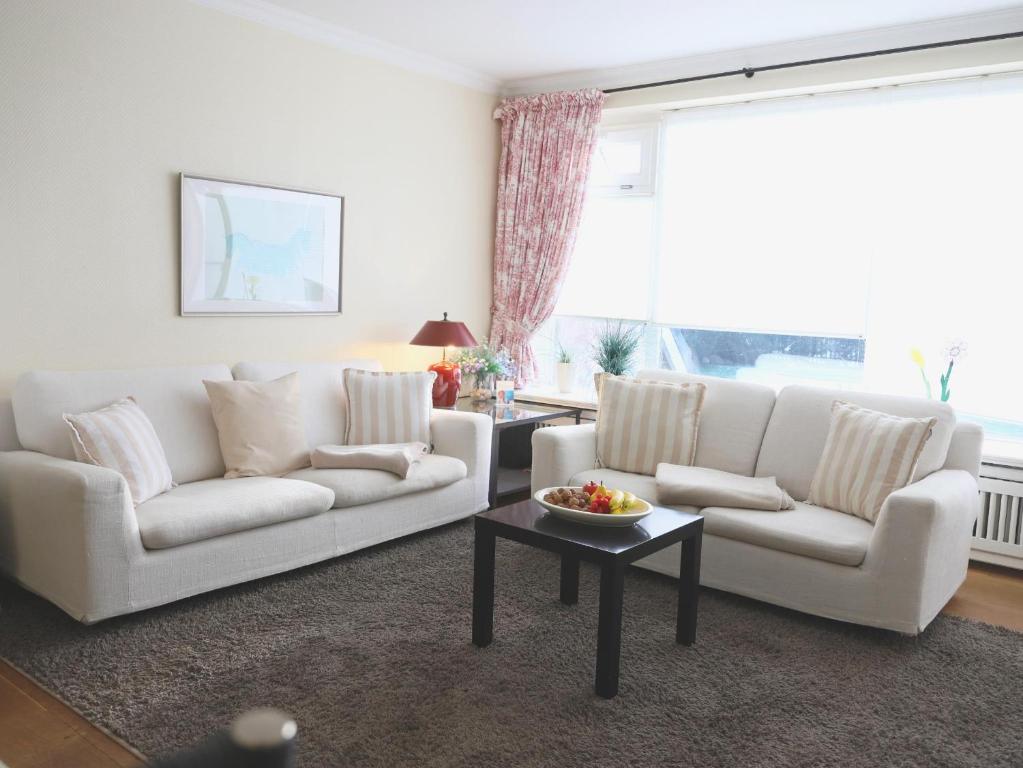a living room with two white couches and a table at Ostertresker 78, DHH in Tinnum