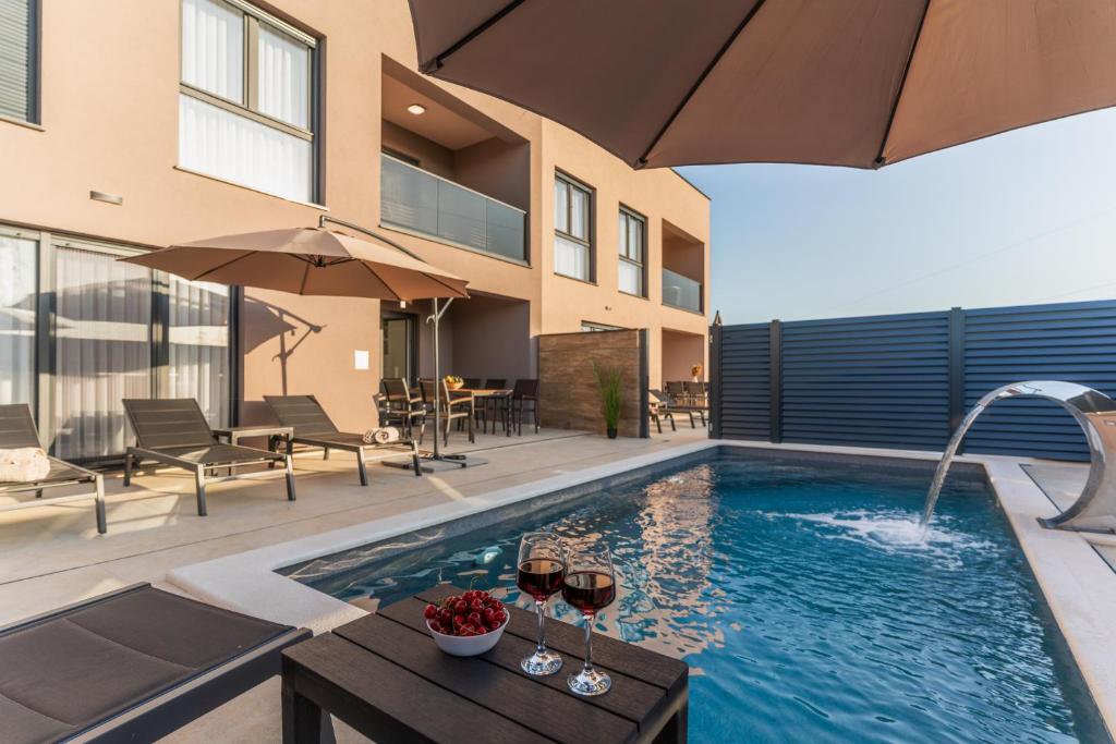 a swimming pool with a table and glasses of wine at The Sun in Ninski Stanovi
