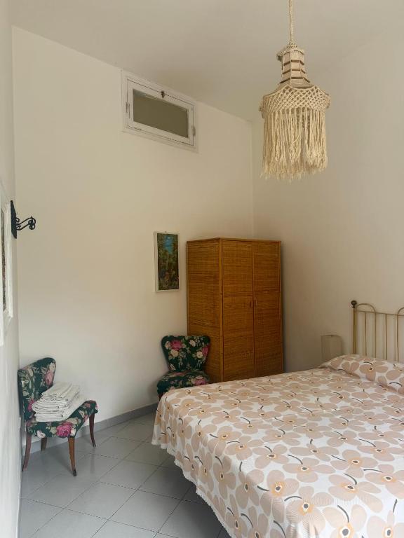 una camera con un letto e due sedie e un lampadario a braccio di FM Apartaments Forio a Ischia