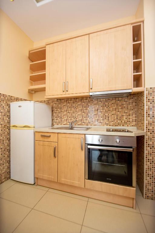 a kitchen with wooden cabinets and a refrigerator at Apartmani Becici in Bečići