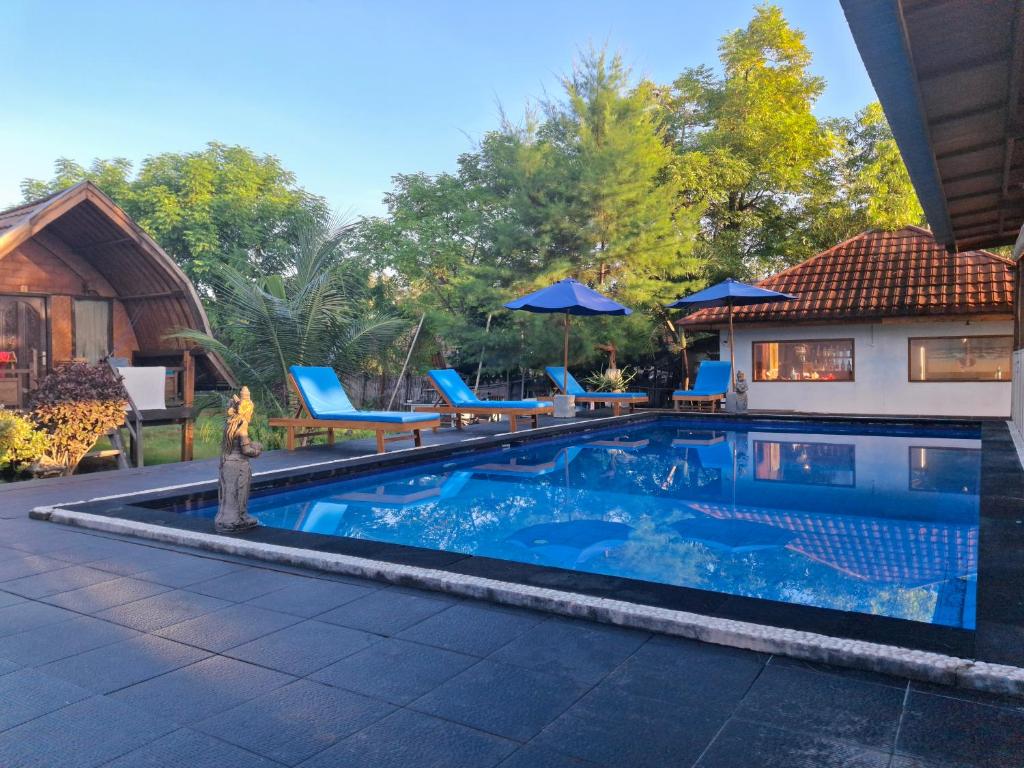 ギリ・アイルにあるGusung Indah Bungalow Gili Airの家の隣にある椅子とパラソルのあるプール