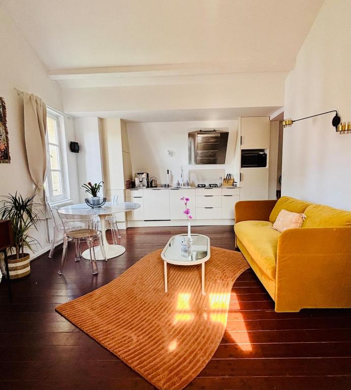 a living room with a yellow couch and a table at La Cour Dudon - Amazing & central appartment in Bordeaux in Bordeaux