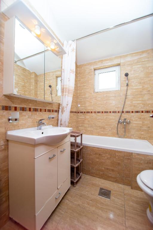 a bathroom with a sink and a tub and a mirror at Apartmani Becici in Bečići