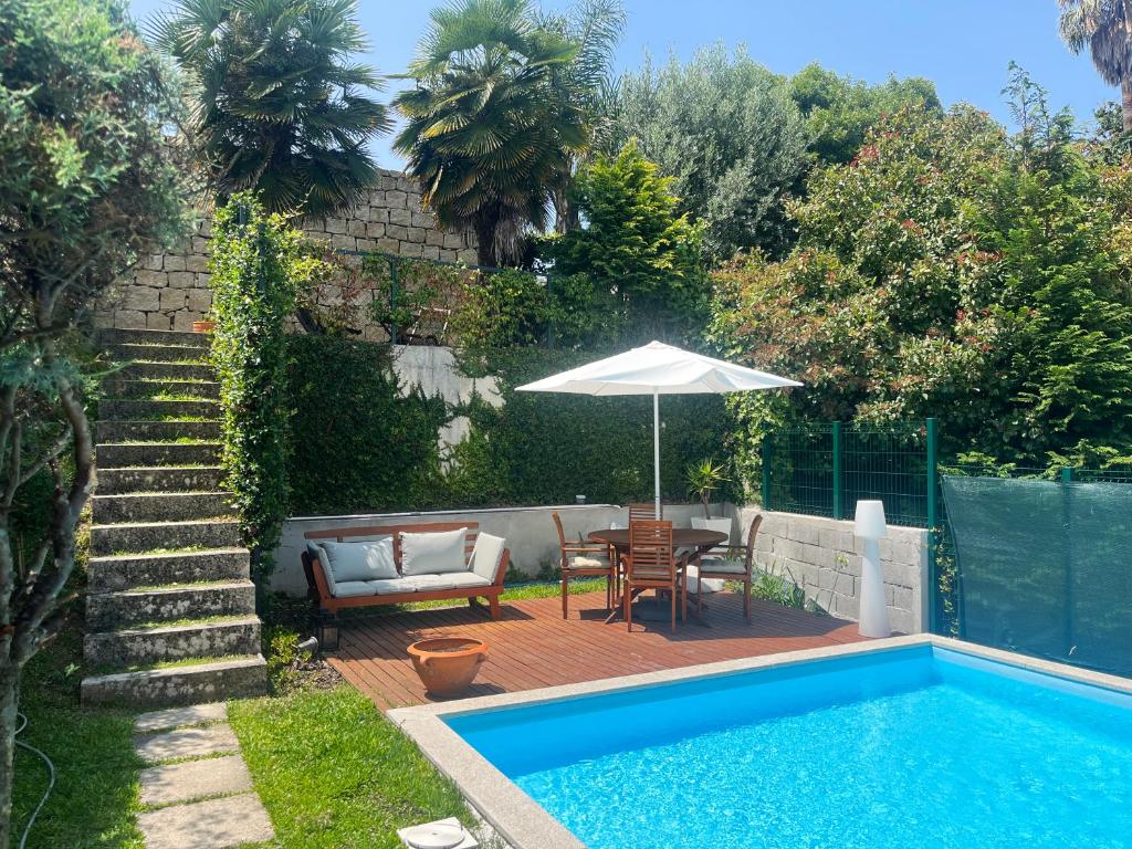 a swimming pool with an umbrella and a table and a chair at Signature Guesthouse 2 in Porto