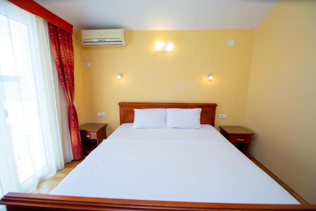 a bedroom with a white bed and a window at Apartmani Becici in Bečići