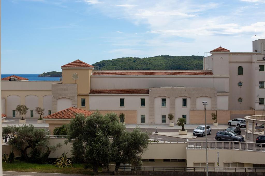 a large building with cars parked in a parking lot at Apartmani Becici in Bečići