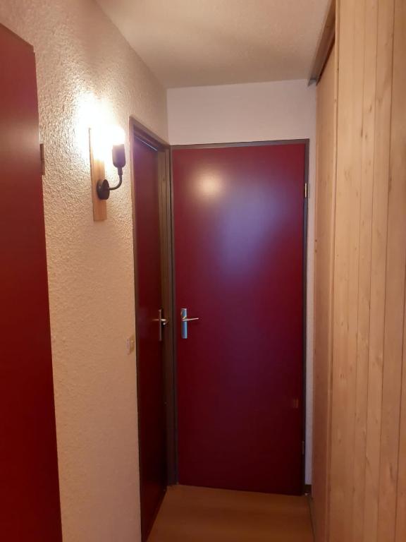 une porte rouge foncé dans une pièce avec une lumière dans l'établissement studio gresse en vercors, à Gresse-en-Vercors