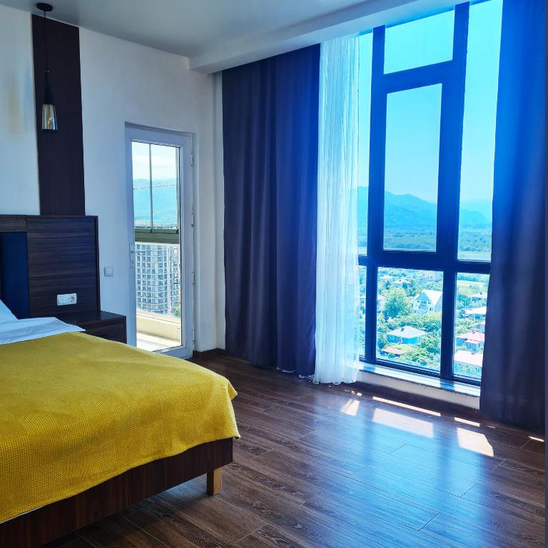 a bedroom with a yellow bed and a large window at Panoramic #1 Sea Mountain View 1BR apartment Living Room, Balcony, Kitchen in Batumi