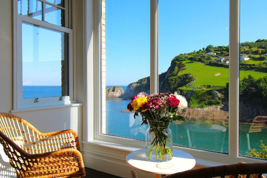 un jarrón de flores en una mesa frente a una ventana en Beachfront Luxury Edwardian Retreat With Sea View, en Combe Martin