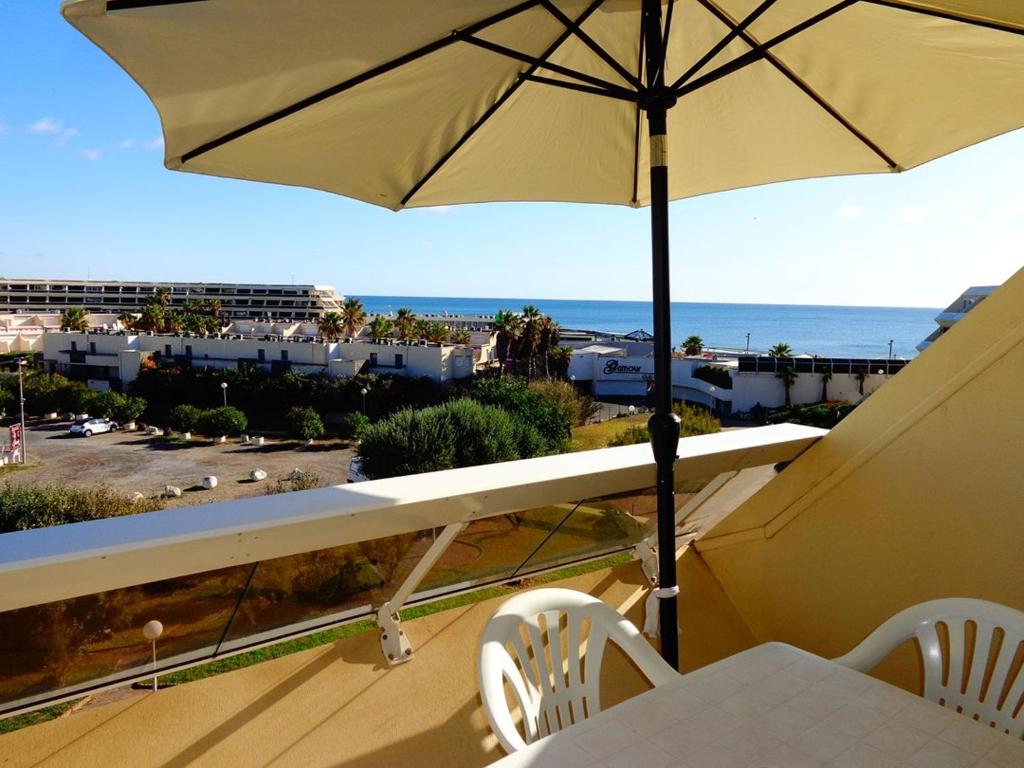 - un balcon avec un parasol, une table et des chaises dans l'établissement Studio Héliopolis E1 - 2 personnes, au Cap d'Agde