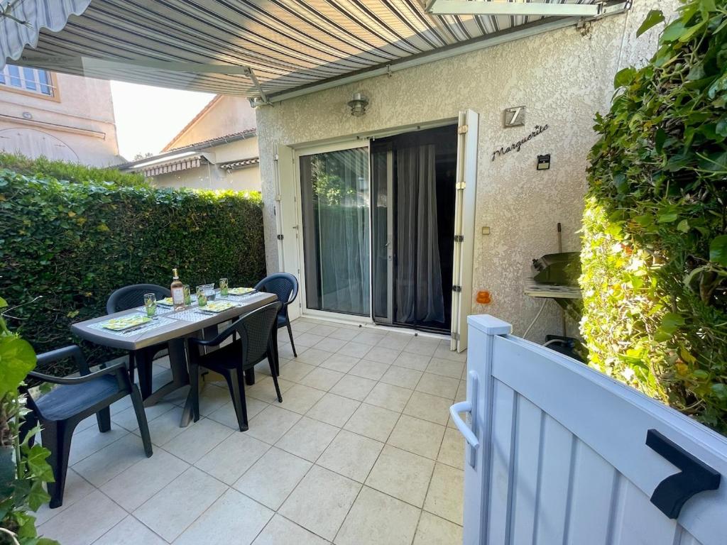 un patio avec une table et des chaises et une clôture dans l'établissement Maisonnette avec terrasse à 300m de la plage 2 étoiles, à Saint-Georges-de-Didonne