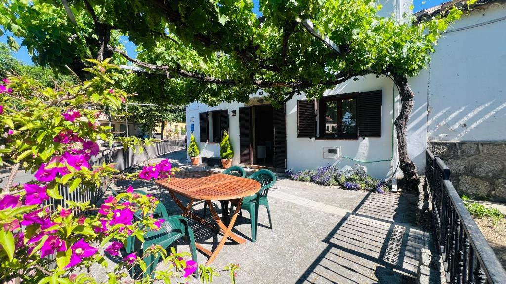 un patio con tavolo, sedie e fiori di Villa Revolcona a La Adrada