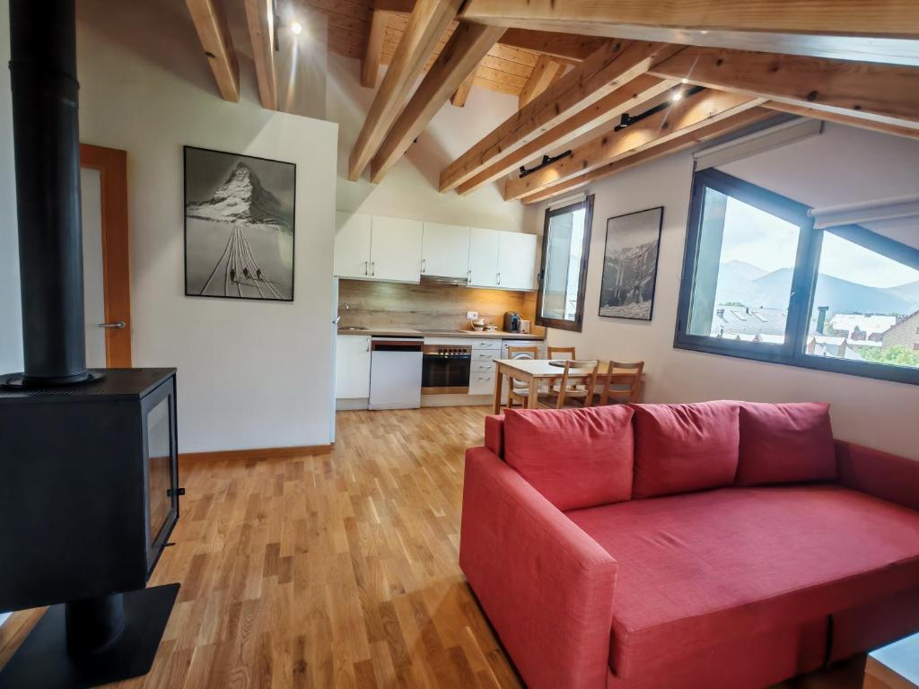 a living room with a red couch and a kitchen at Apartamento abuhardillado y espacioso Aüt 3 in Pla de l'Ermita