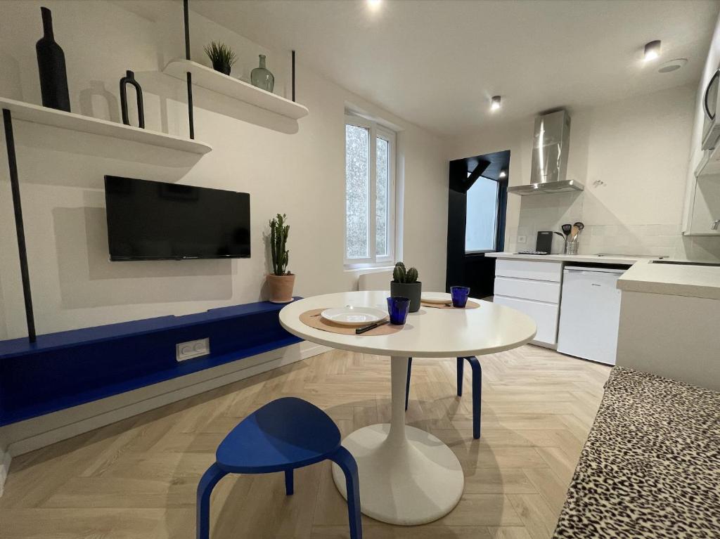 une cuisine avec une table blanche et un tabouret bleu dans l'établissement 2 pièces Pau centre-ville, à Pau