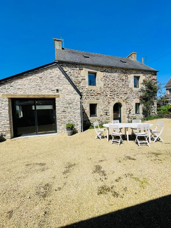 une maison en pierre avec une table et des chaises devant elle dans l'établissement Ty Bugale, 6 personnes, proche mer, à Plestin-les-Grèves