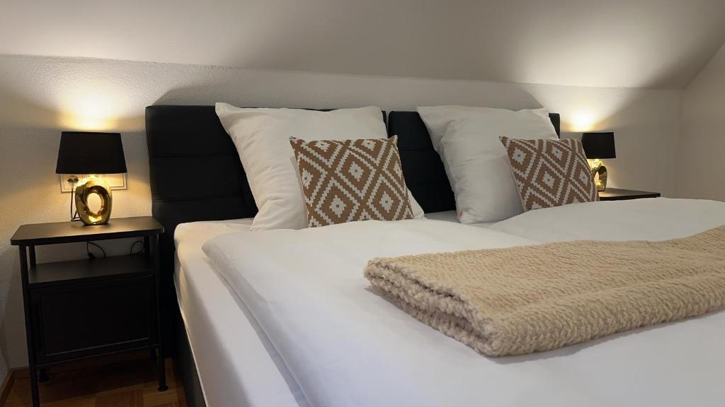 a bedroom with a white bed with pillows and a night stand at Deluxe Apartment in Jettingen-Scheppach