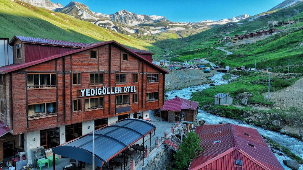 a building with a sign on it next to a river at Yedigoller Hotel & Restaurant in Uzungöl