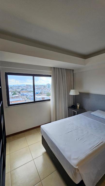 a bedroom with a large bed and a large window at Flat 01 Celita Franca Business in Feira de Santana