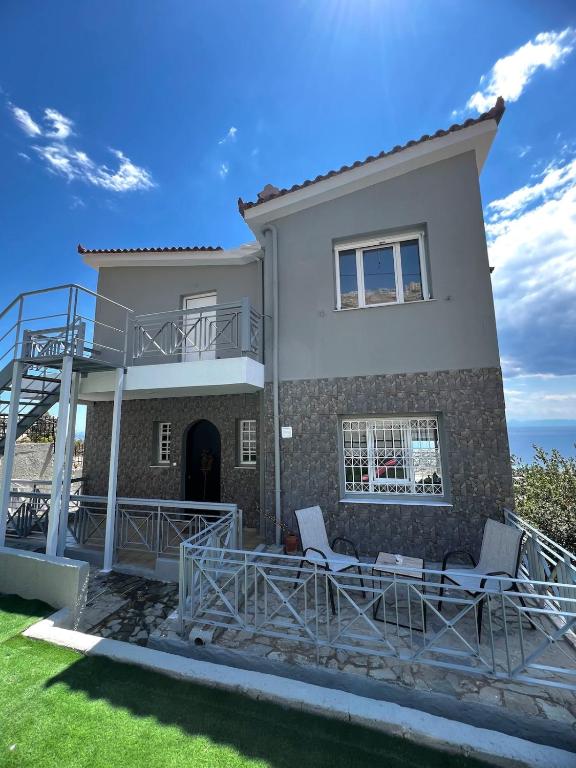 a house with a balcony and two chairs at Eleni's Seaview House in Saronida
