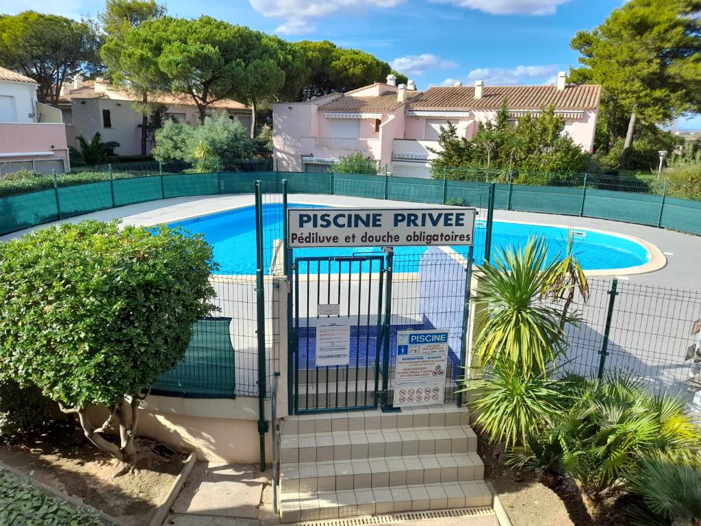 une clôture avec un panneau en face d'une piscine dans l'établissement La Mouette rieuse, au Cap d'Agde