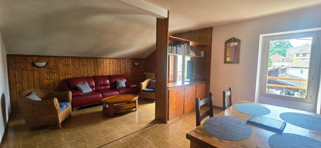 un salon avec un canapé rouge et une table dans l'établissement Le Clémille, à Thonon-les-Bains