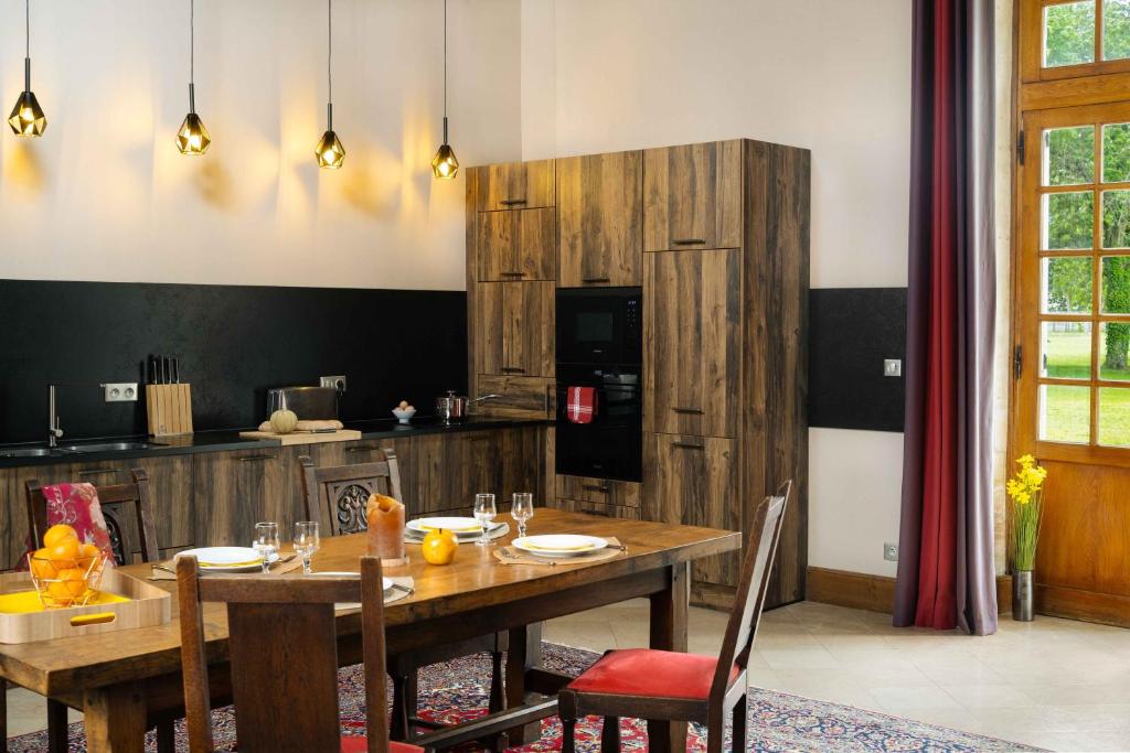 une salle à manger avec une table et une cuisine dans l'établissement Gîtes La Grande Ferme Crépon - à la campagne 5mn d'Arromanches et 10mn de Bayeux, à Crépon