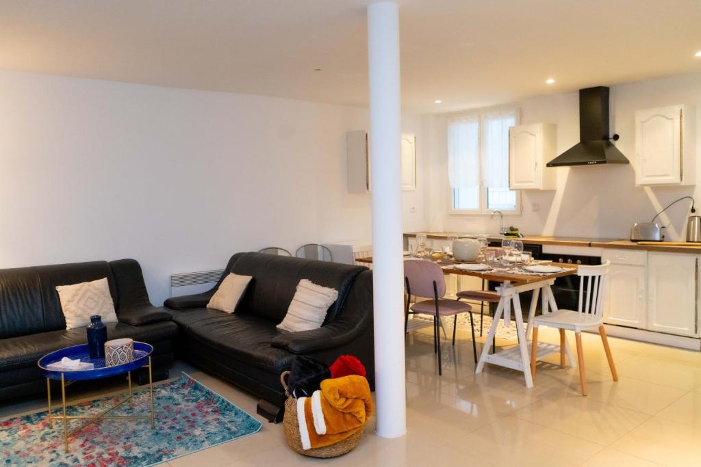 un salon avec un canapé noir et une cuisine dans l'établissement Maison urbaine familiale, à Béziers