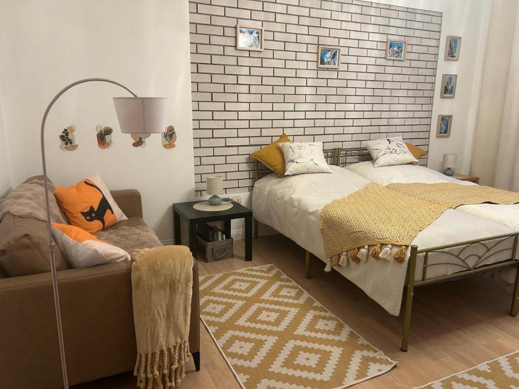 1 dormitorio con 2 camas, sofá y pared de ladrillo en Ferien Wohnung Katzenruh, en Lauenburgo/Elbe