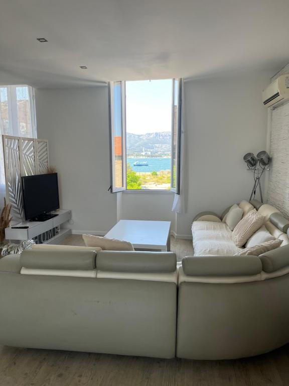 un salon avec un canapé blanc et une grande fenêtre dans l'établissement Duplex T4 vue mer, à La Seyne-sur-Mer