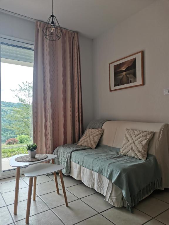 une chambre avec un lit, une table et une fenêtre dans l'établissement Appartement T2 avec piscine Vallée du Tarn, à Trébas