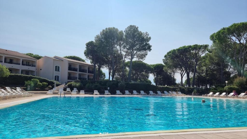 une grande piscine avec des chaises et des arbres dans l'établissement Chez K&D by Laure, à Saint-Raphaël