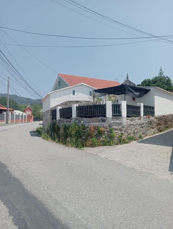 a white building with a fence in front of a street at La Casita in Cangas de Morrazo