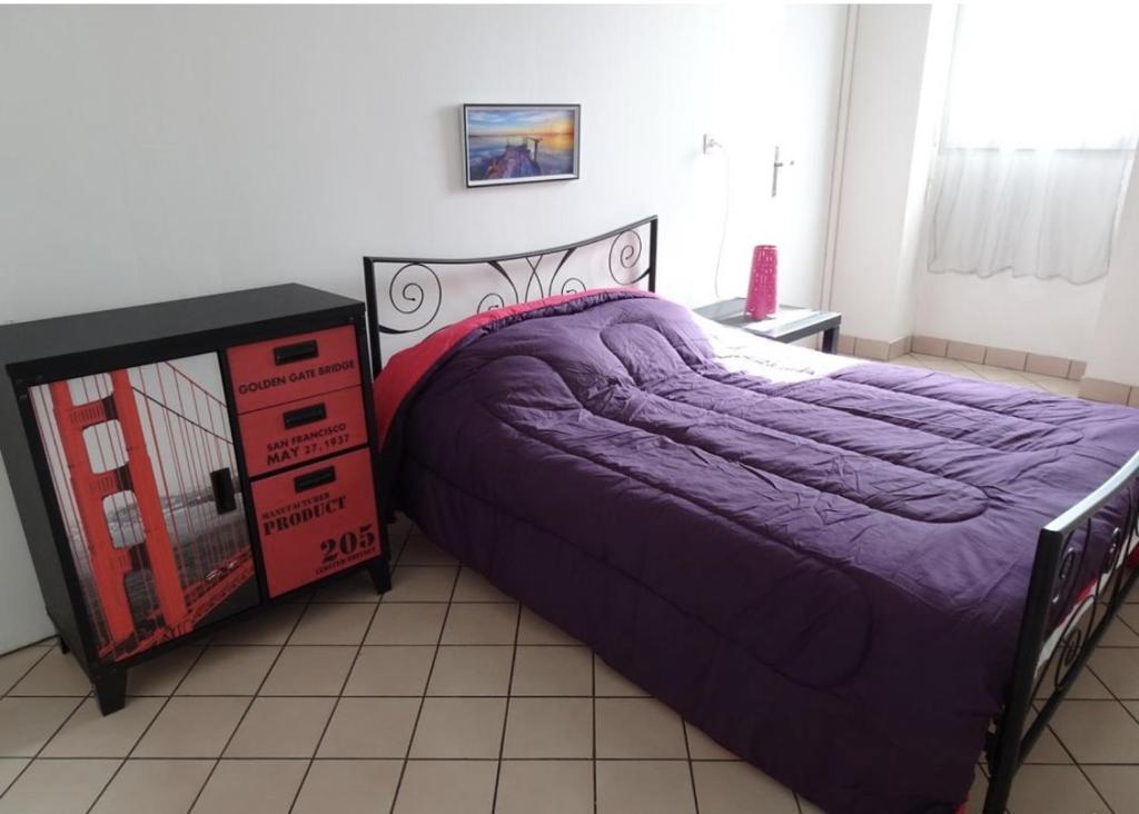 a bedroom with a purple bed and a dresser at Le Paquebot - Near Les Chantiers de l'Atlantique in Saint-Nazaire