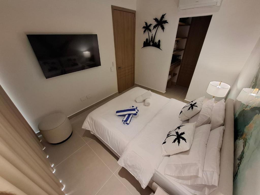 - une chambre avec un lit blanc et un canapé blanc dans l'établissement Baia Kristal - Vacaciones Cartagena Colombia, à Carthagène des Indes