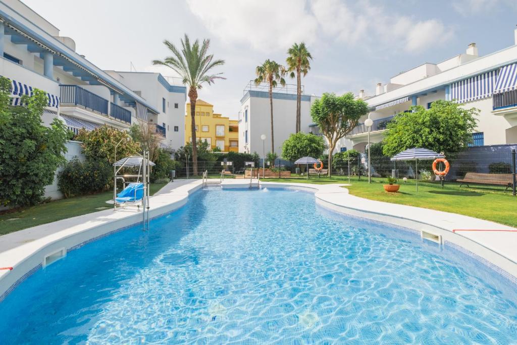 a swimming pool in a resort with palm trees and buildings at Apartamento Vista Azul in Costa Ballena