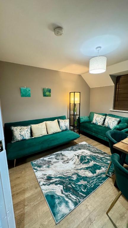 a living room with a green couch and a rug at Emerald dream house in Swindon